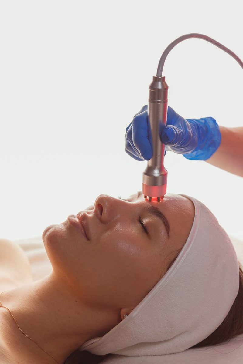 Young woman getting microcurrents skin cleansing and face treatment at beauty salon